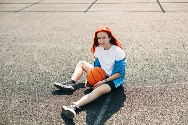 Een charmant tienermeisje met een basketbal rust na een training. Een meisje op het sportveld. Sport, training, gezonde levensstijl — Stockfoto