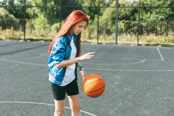 Seorang gadis remaja yang cantik memimpin basket di lapangan olahraga, seorang gadis belajar untuk bermain basket — Stok Foto