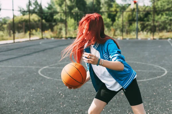 Μια όμορφη έφηβη οδηγεί μπάσκετ στο γήπεδο. Ένα κορίτσι μαθαίνει μπάσκετ. — Φωτογραφία Αρχείου