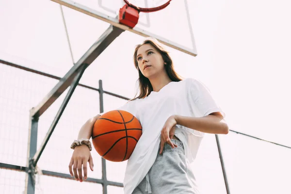 Retrato de uma menina jogador de basquete pensativo com uma bola em suas mãos. Basquete, esportes, estilo de vida saudável — Fotografia de Stock