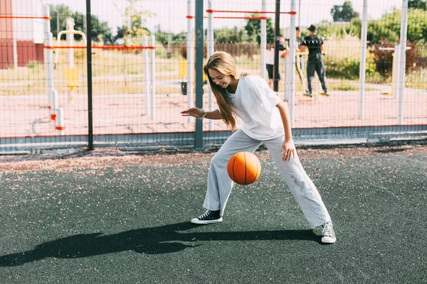 Seorang gadis remaja memimpin bola basket di lapangan olahraga, seorang gadis melindungi bola selama permainan — Stok Foto