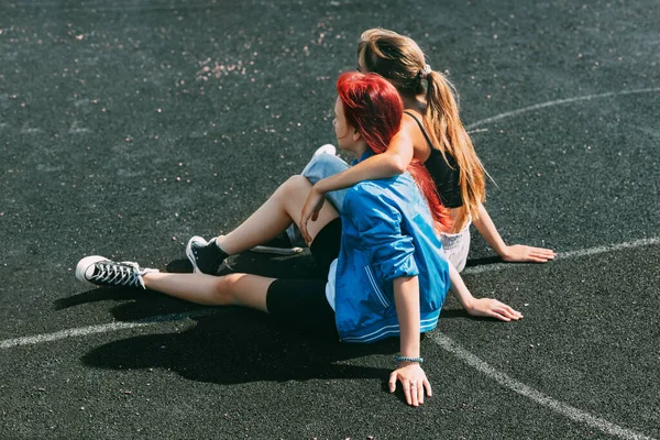 Dospívající dívky sedí na sportovním hřišti v parku nebo na školním stadionu. Přátelé, přátelství, společný čas — Stock fotografie