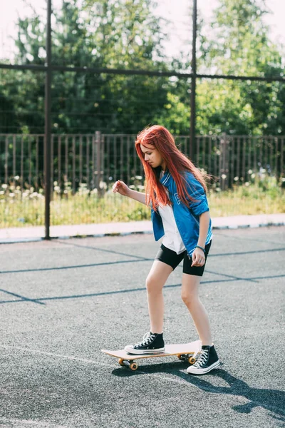 かわいいですティーン女の子は、スポーツフィールド上のスケートボードに乗る — ストック写真