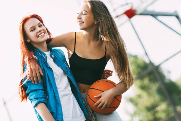Dua gadis lucu dengan pelukan basket satu sama lain setelah permainan atau latihan. Konsep olahraga dan persahabatan — Stok Foto