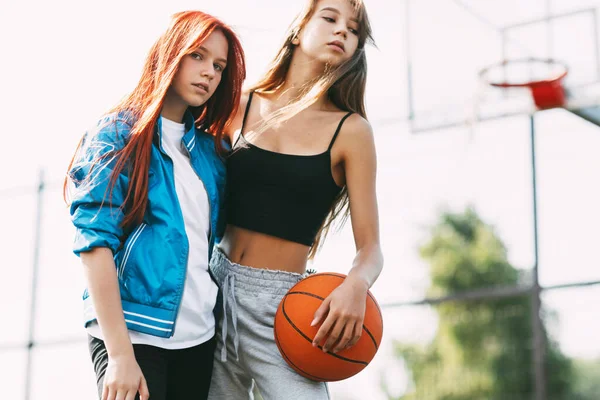 Porträt zweier charmanter Mädchen mit einem Basketball auf dem Sportplatz. Freundschaft, beste Freunde, Sport — Stockfoto