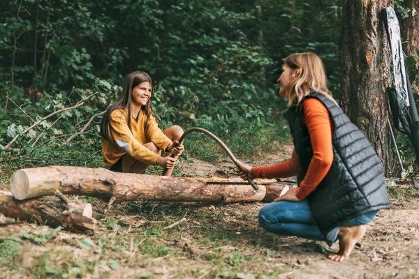 Una madre e sua figlia stanno segando un albero caduto per un incendio. Raccolta legna da ardere, falò, picnic — Foto Stock