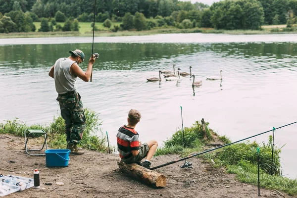 Ένας νεαρός μαθαίνει στα παιδιά του να ψαρεύουν κατά τη διάρκεια οικογενειακών διακοπών σε κάμπινγκ. Χόμπι, διακοπές, Σαββατοκύριακα, ψάρεμα — Φωτογραφία Αρχείου