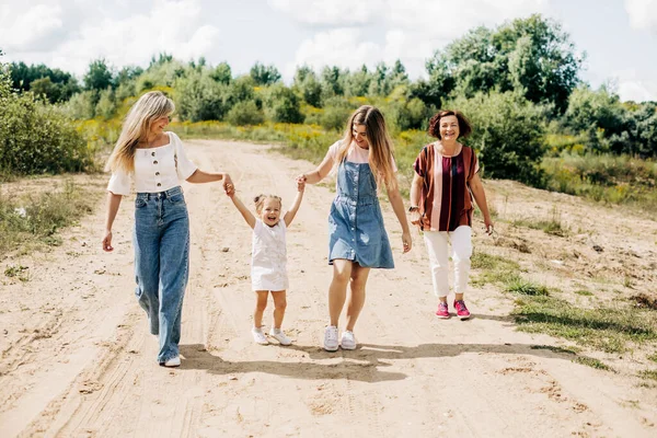 Verschillende generaties vrouwen van dezelfde familie lopen langs een onverharde weg buiten de stad, genietend van de tijd die ze samen hebben doorgebracht. — Stockfoto