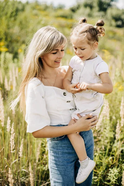 Een jonge moeder houdt haar kleine charmante dochter in haar armen — Stockfoto