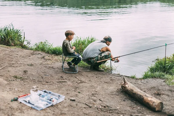 Ένας νεαρός μαθαίνει στα παιδιά του να ψαρεύουν κατά τη διάρκεια οικογενειακών διακοπών σε κάμπινγκ. Χόμπι, διακοπές, Σαββατοκύριακα, ψάρεμα — Φωτογραφία Αρχείου