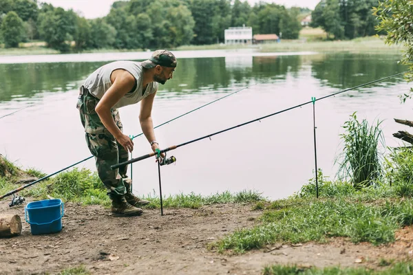 Ένας νεαρός ψαράς πιάνει ψάρια σε λίμνη ή ποτάμι, προετοιμάζει τάκλιν και δόλωμα. Χόμπι, Σαββατοκύριακα, ψάρεμα — Φωτογραφία Αρχείου