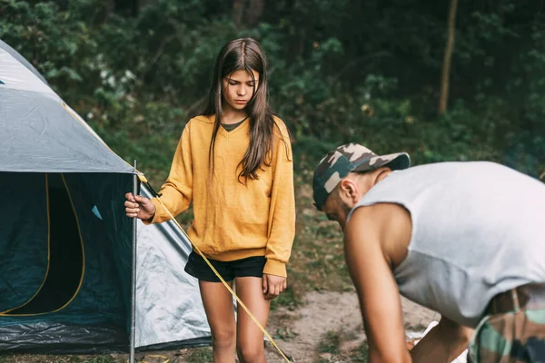 Um pai e uma filha felizes montam uma tenda de campismo. Tempo de família, descanso familiar, cuidados — Fotografia de Stock