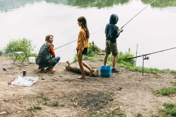 Μια ευτυχισμένη οικογένεια ψαρεύει στην όχθη ενός ποταμού ή μιας λίμνης. Περνάμε χρόνο μαζί, οικογενειακό χρόνο, οικογενειακές διακοπές — Φωτογραφία Αρχείου