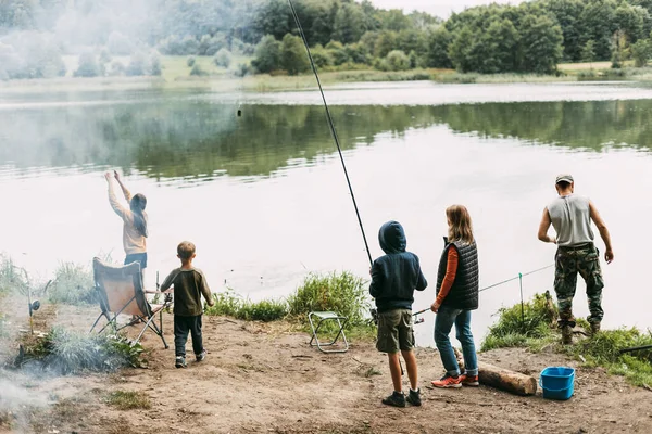 Μια ευτυχισμένη οικογένεια ψαρεύει στην όχθη ενός ποταμού ή μιας λίμνης. Περνάμε χρόνο μαζί, οικογενειακό χρόνο, οικογενειακές διακοπές — Φωτογραφία Αρχείου