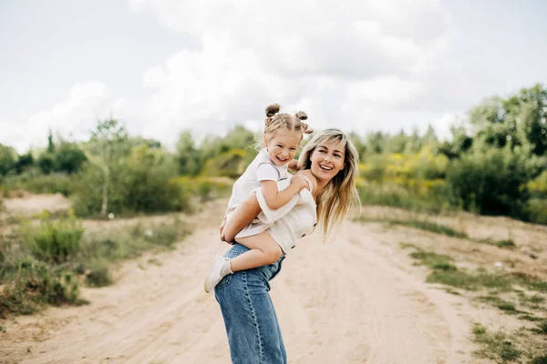 Une jeune mère roule sa petite fille sur le dos, le bébé étreint sa mère — Photo