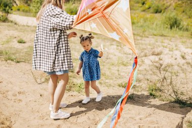 Sevimli küçük bir kız eğleniyor ve ablasıyla uçurtma fırlatıyor.