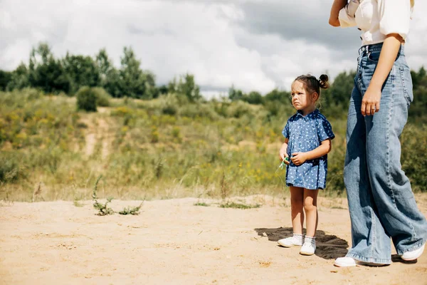 Uma menina está de pé com sua mãe em uma estrada de terra — Fotografia de Stock