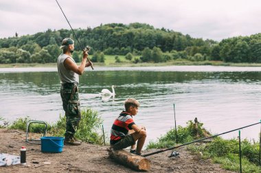 Genç bir adam çocuklarına kamp alanında aile tatili sırasında balık tutmayı öğretiyor. Hobiler, tatiller, hafta sonları, balıkçılık