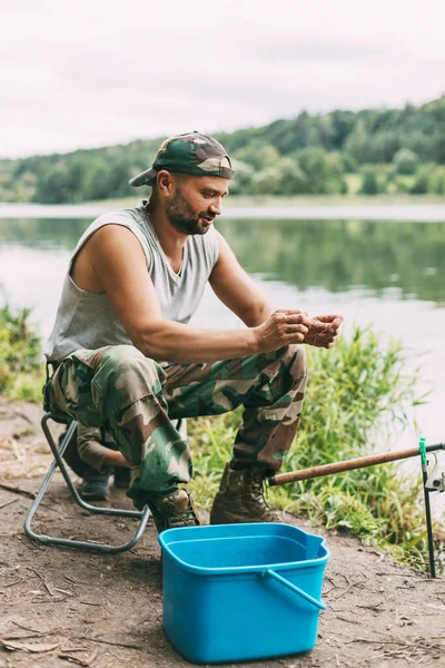 Ένας νεαρός ψαράς πιάνει ψάρια σε λίμνη ή ποτάμι, προετοιμάζει τάκλιν και δόλωμα. Χόμπι, Σαββατοκύριακα, ψάρεμα — Φωτογραφία Αρχείου