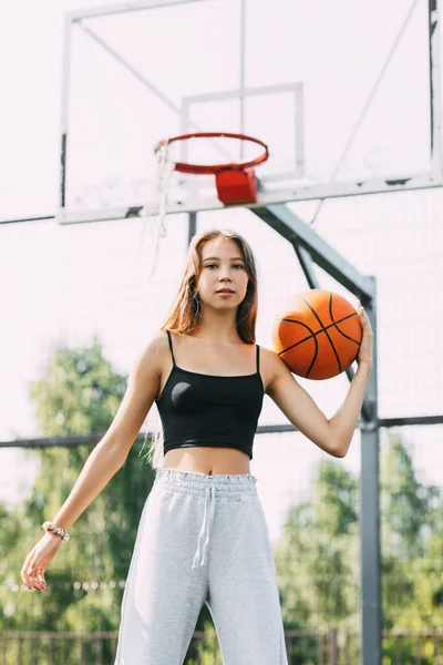 Potret pemain basket wanita muda. Gadis remaja yang cantik bermain basket. dalam pakaian olahraga bermain basket — Stok Foto