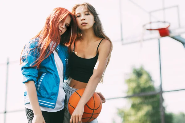 Porträt zweier charmanter Mädchen mit einem Basketball auf dem Sportplatz. Freundschaft, beste Freunde, Sport — Stockfoto