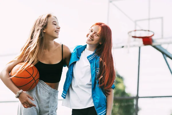 Dua gadis lucu dengan pelukan basket satu sama lain setelah permainan atau latihan. Konsep olahraga dan persahabatan — Stok Foto