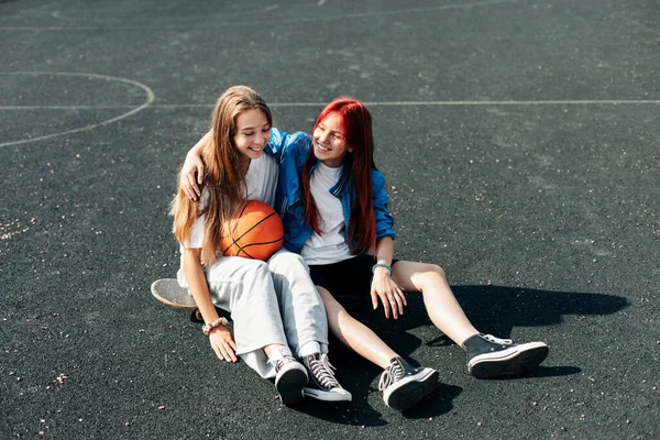 Um par de adolescentes em uma quadra de rua esportiva com um estilo de vida de basquete relaxar depois de um jogo e conversar. O conceito de esportes e um estilo de vida saudável — Fotografia de Stock