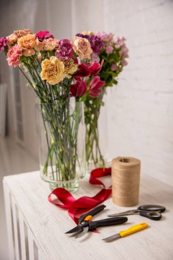 Çiçekçinin işyeri. Masada çalışmaya başlamadan önce aletler ve çiçekler. Çiçekçi bıçağı, makas, budama makası, bant, ip. Özel ders. Adım adım. Yüksek kalite fotoğraf