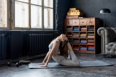 Spor takım elbiseli genç bir kadın çatı katında esneme egzersizleri yapıyor. İzolasyon salgını sırasında spor, online jimnastik ve yoga dersleri. Sağlıklı yaşam tarzı.