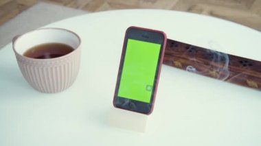 Evde yeşil ekran şablonu akıllı telefon, masada alet. Meditasyon için kızılderili tütsüsü. Uzayı kopyala Modern teknoloji ve bilgi kavramı.