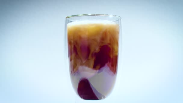 Mléko se rozpouští v kávě nebo čajovém nápoji. sklo s dvojitými stěnami na bílém pozadí — Stock video
