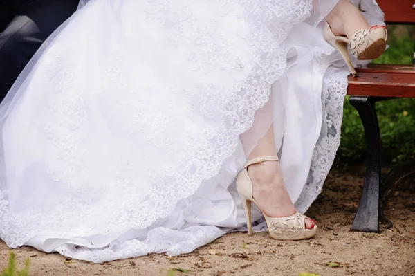 Jarretera en la pierna de una novia, esbelta novia sexy en vestido de lujo de boda que muestra su liga de seda con cinta dorada. mujer tiene una preparación final para la ceremonia de la boda. Momentos de boda — Foto de Stock