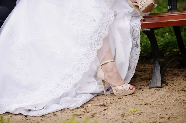Подвязка на ноге невесты, стройная сексуальная невеста в свадебном роскошном платье, показывающем ее шелковую подвязку с золотой лентой. женщина имеет окончательную подготовку к свадебной церемонии. Моменты в день свадьбы — стоковое фото