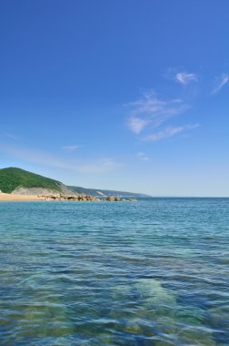 Deniz ve dağlar açık bir gökyüzü altında