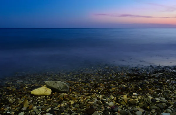 Sea and the pebble beach at sunset — Stock Photo, Image