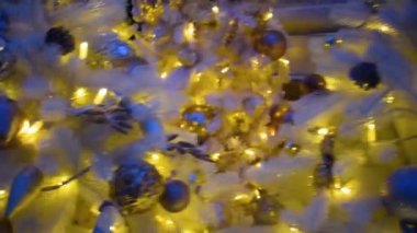 Gümüş süslemeli beyaz Noel ağacı ve gece şehrinde asılı duran altın ampuller. Kamera, odağını kaybetti. Kutlama konsepti, şenlikli atmosfer. Şehrin Gece Sokağında