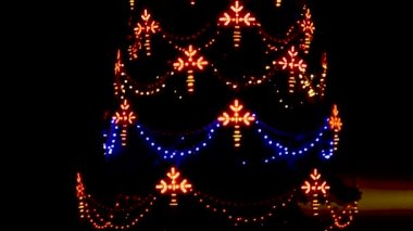 Yanıp sönen bir çelengi olan Noel ağacı. Geceleri parlayan bir Noel ağacı ışığını kapat. Açık havada parlayan süslü yeni yıl ağacı. 