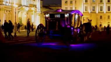 Akşam vakti Winter Palace 'ın önündeki Çar at arabasının açık hava manzarası turistik bir mekan. Koç meydanda ve kadınlar geleneksel Rus kıyafetleri içinde..