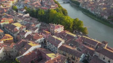 Adige nehri üzerinde köprüleri olan Verona şehrinin hava manzarası. İtalya 'da kırmızı kiremit çatılı ortaçağ binaları. 4K 'da günbatımında hava görüntüsü.