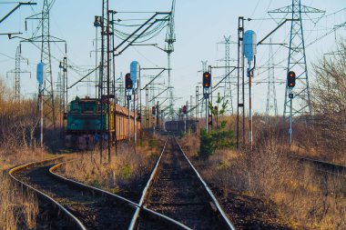 Tozlu elektrikli yük treni ve kırmızı semaforlar.