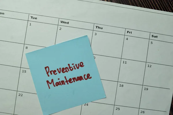 Preventive Maintenance write on sticky note and Calendar date isolated on Wooden Table.