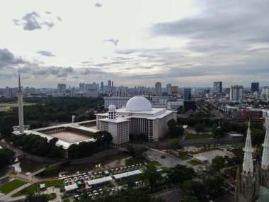 İstiklal Camii 'nin havadan görünüşü. Güneydoğu Asya 'nın en büyük camii ve Jakarta şehir manzaralı gürültü bulutu. JAKARTA - Endonezya. 30 Ocak 2021
