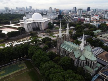 Jakarta Katedrali ve İstiklal Camii 'nin havadan görünüşü. Güneydoğu Asya 'nın en büyük camii ve Jakarta şehir manzaralı gürültü bulutu. JAKARTA - Endonezya. 30 Ocak 2021