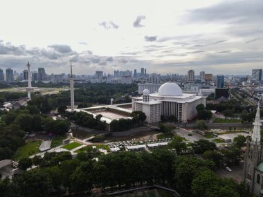 Aerial view of Istiqlal Mosque. It is the largest mosque in Southeast Asia and noise cloud with Jakarta cityscape. JAKARTA - Indonesia. January 30, 2021 clipart
