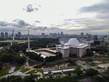 İstiklal Camii 'nin havadan görünüşü. Güneydoğu Asya 'nın en büyük camii ve Jakarta şehir manzaralı gürültü bulutu. JAKARTA - Endonezya. 30 Ocak 2021