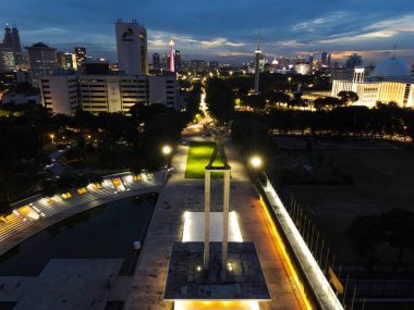 Jakarta şehir merkezindeki Batı Irian Özgürlük Anıtı 'nın havadan görünüşü ve Jakarta şehir manzarasıyla günbatımında gürültü bulutu. JAKARTA - Endonezya. 30 Ocak 2021