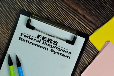 FERS - Federal Employees Retirement System write on a paperwork isolated on Wooden Table. clipart