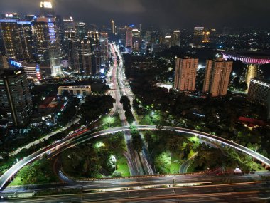 Geceleri büyük, modern bir şehrin göz kamaştırıcı gece silueti. Semanggi, Jakarta, Endonezya. Gürültü bulutlu gökdelenler ve otobanlar üzerinde hava manzarası. JAKARTA - Endonezya. 4 Şubat 2021