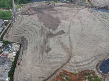 Hava görüntüsü. Dağ gibi büyük çöplükler. Traktör, 15 Şubat 2021 'de Bekasi - Endonezya' da yağmur ve şehir manzarası üzerine gürültü bulutu ile çöpleri topluyor.
