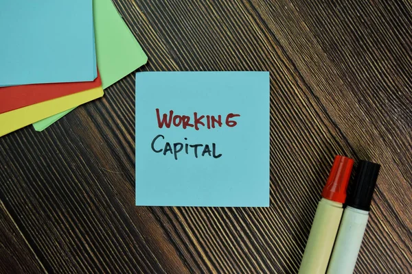 Working Capital write on sticky notes isolated on Wooden Table.